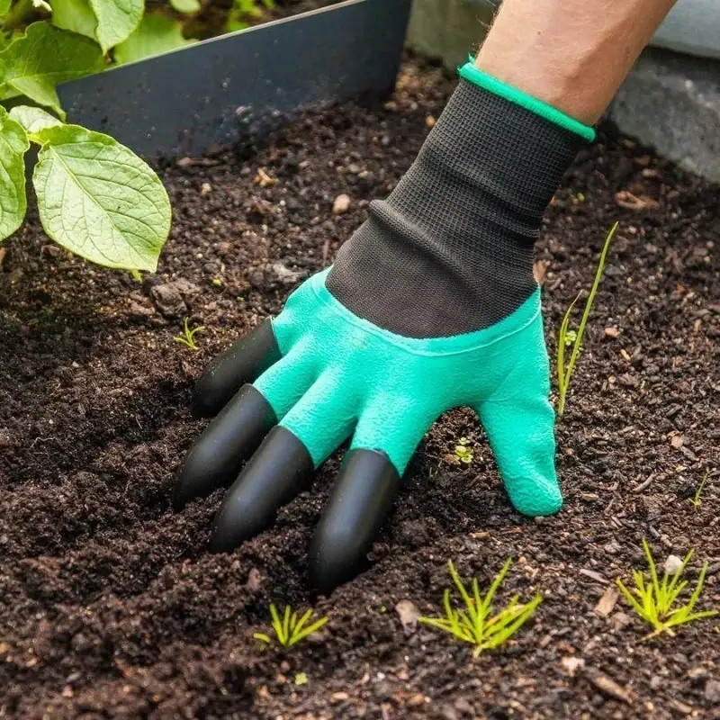 Green and black garden glove working in soil